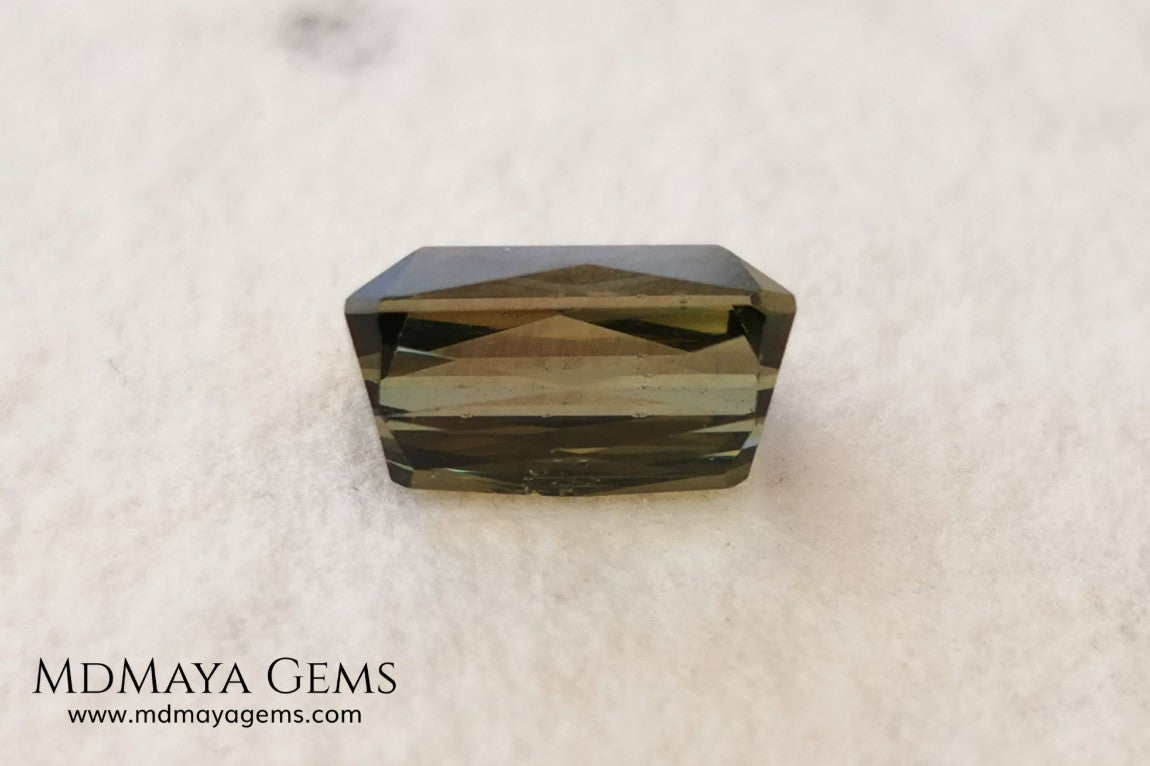 Bicolor Green Tourmaline 2.33 ct, emerald cut. This olive green bicolor tourmaline shows a orange - peach color depending on how the light falls on it. It has a good quality of cut and will look very beautiful in any piece of jewelry. A natural untreated gem at a low price.