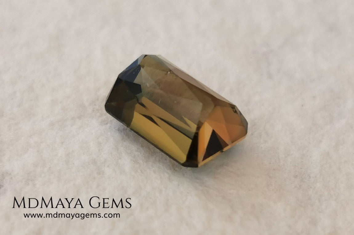 Bicolor Green Tourmaline 2.33 ct, emerald cut. This olive green bicolor tourmaline shows a orange - peach color depending on how the light falls on it. It has a good quality of cut and will look very beautiful in any piece of jewelry. A natural untreated gem at a low price.