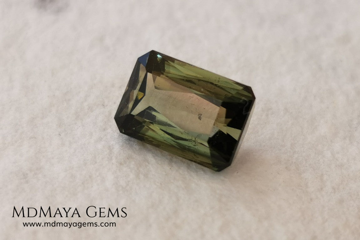 Bicolor Green Tourmaline 2.33 ct, emerald cut. This olive green bicolor tourmaline shows a orange - peach color depending on how the light falls on it. It has a good quality of cut and will look very beautiful in any piece of jewelry. A natural untreated gem at a low price.