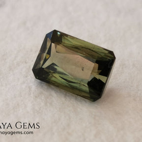 Bicolor Green Tourmaline 2.33 ct, emerald cut. This olive green bicolor tourmaline shows a orange - peach color depending on how the light falls on it. It has a good quality of cut and will look very beautiful in any piece of jewelry. A natural untreated gem at a low price.
