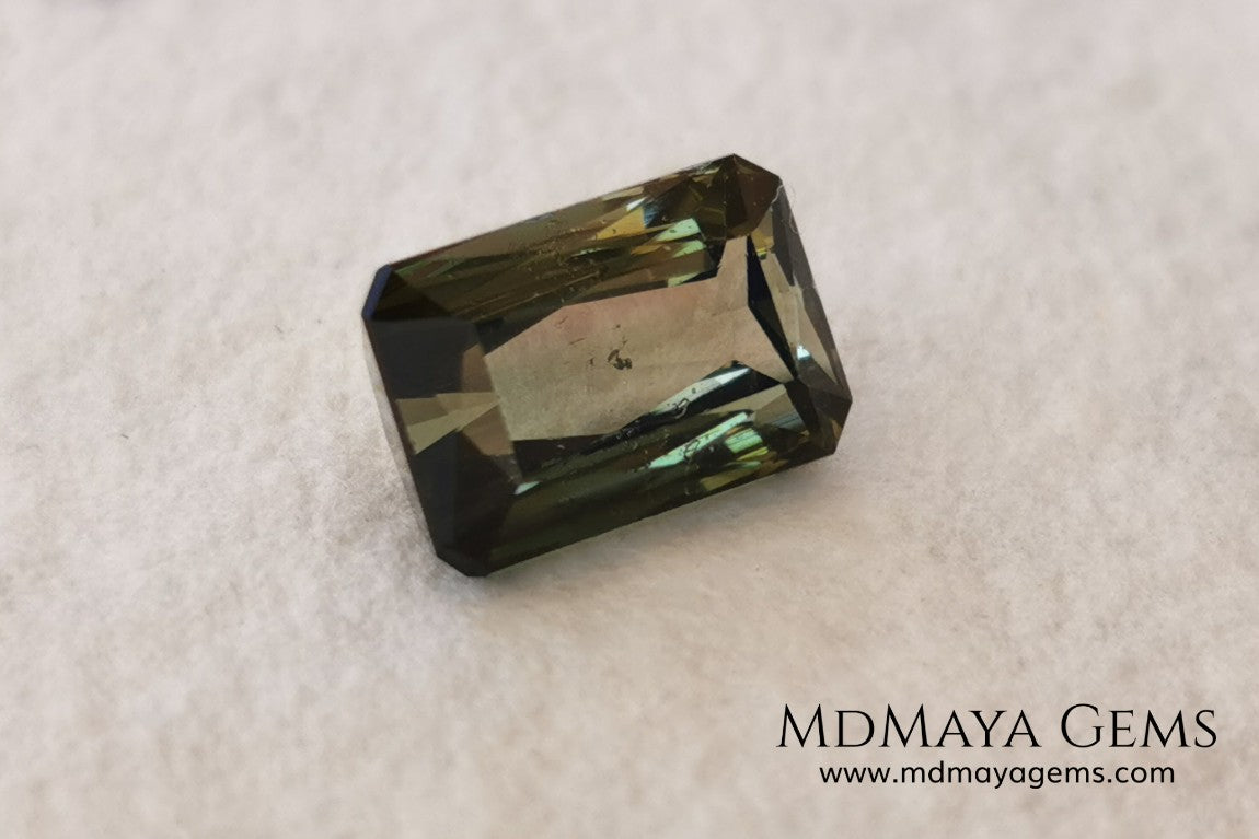 Bicolor Green Tourmaline 2.33 ct, emerald cut. This olive green bicolor tourmaline shows a orange - peach color depending on how the light falls on it. It has a good quality of cut and will look very beautiful in any piece of jewelry. A natural untreated gem at a low price.