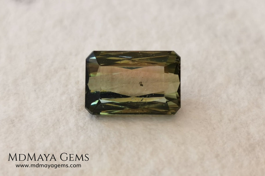 Bicolor Green Tourmaline 2.33 ct, emerald cut. This olive green bicolor tourmaline shows a orange - peach color depending on how the light falls on it. It has a good quality of cut and will look very beautiful in any piece of jewelry. A natural untreated gem at a low price.