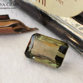Bicolor Green Tourmaline 2.33 ct, emerald cut. This olive green bicolor tourmaline shows a orange - peach color depending on how the light falls on it. It has a good quality of cut and will look very beautiful in any piece of jewelry. A natural untreated gem at a low price.
