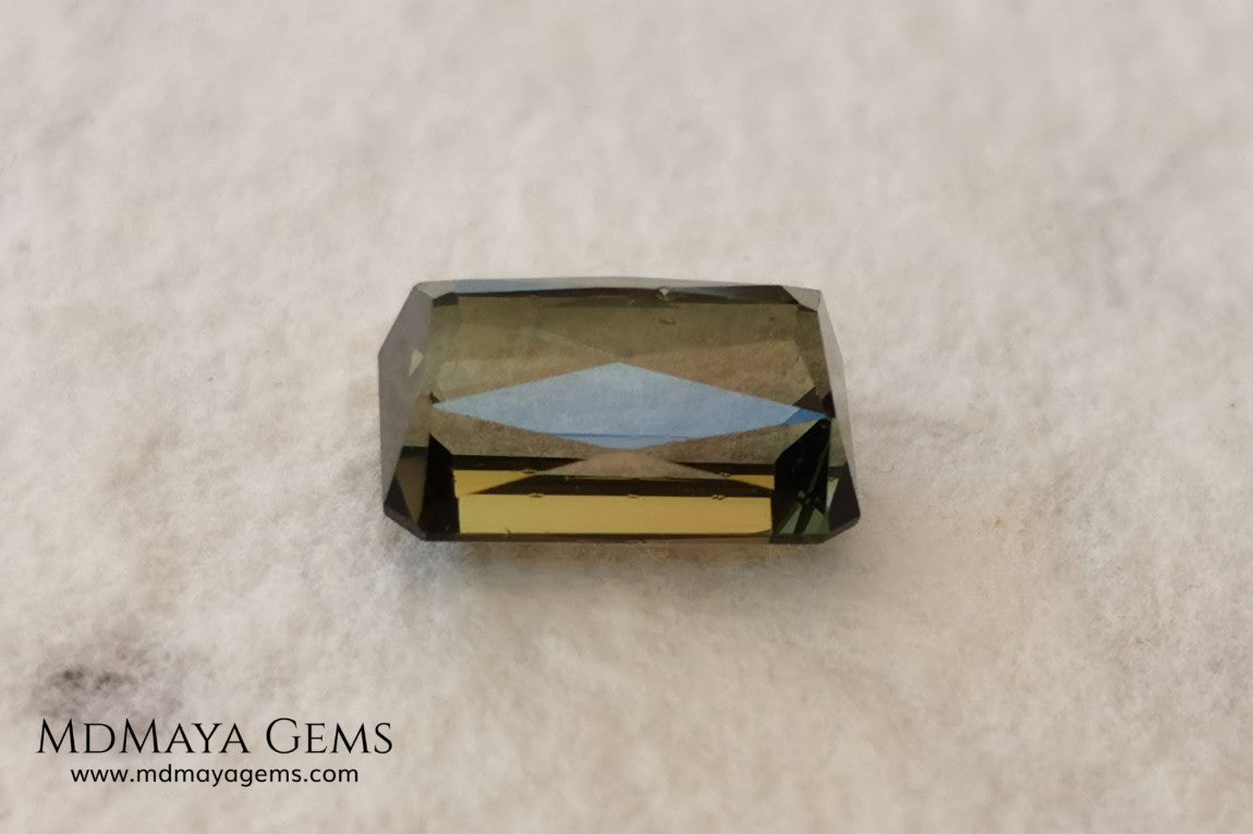 Bicolor Green Tourmaline 2.33 ct, emerald cut. This olive green bicolor tourmaline shows a orange - peach color depending on how the light falls on it. It has a good quality of cut and will look very beautiful in any piece of jewelry. A natural untreated gem at a low price.